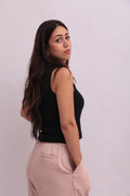 Model wearing a black cropped tank top styled with high-waisted pink trousers, showing the back and side view of the minimalist design.
