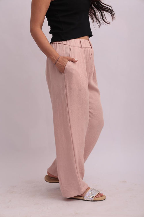 Side view of a model in a black cropped tank top and relaxed pink trousers, showcasing the clean lines and comfortable fit.