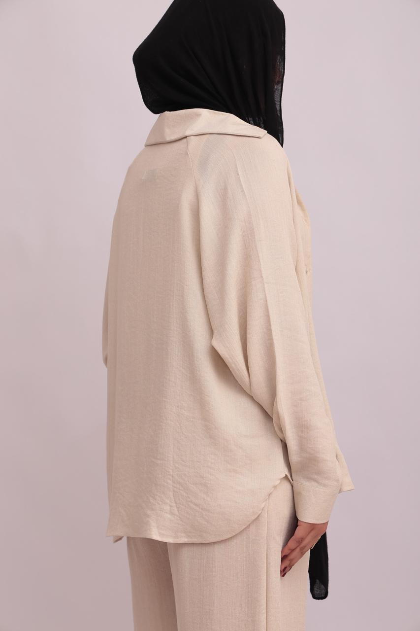 Back view of a model in a black hijab wearing a cream linen overshirt, showcasing its relaxed oversized fit and back yoke details.