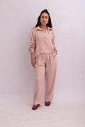 Full-body shot of a model wearing a blush pink linen long-sleeve shirt and matching wide-leg trousers, creating a cohesive casual outfit.