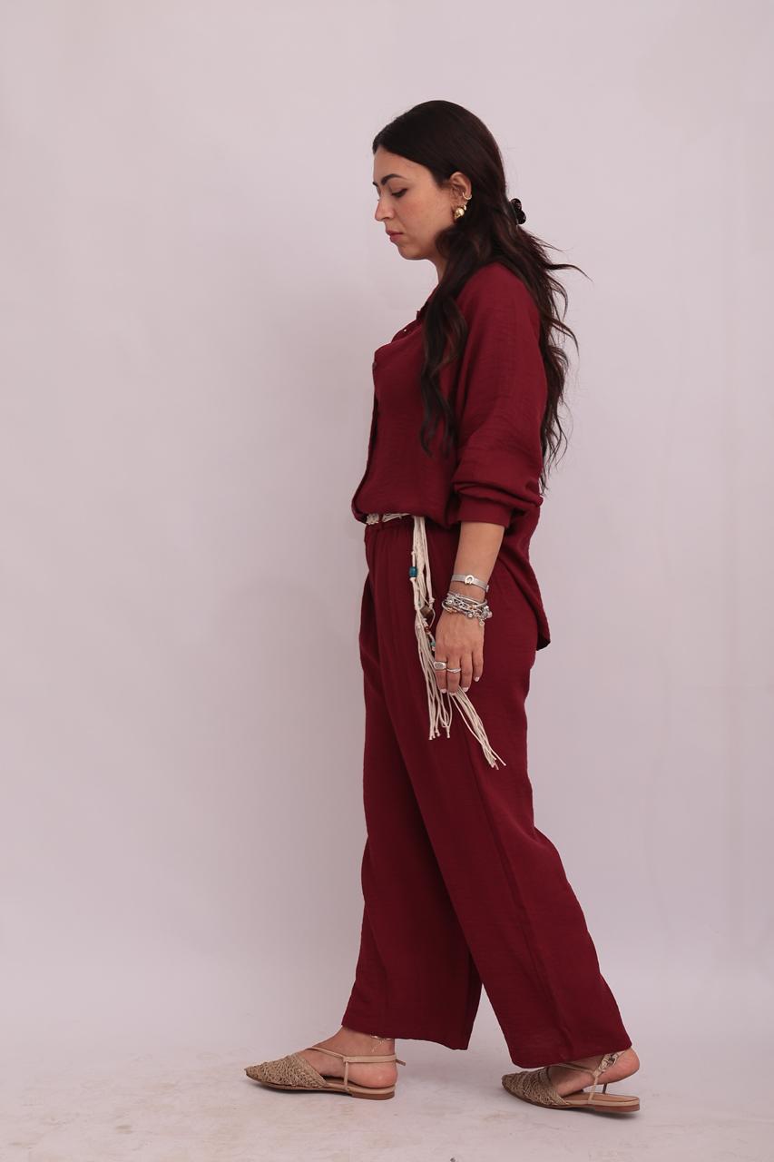 Side view of a model wearing a burgundy linen shirt and matching wide-leg trousers, showing a relaxed summer look.
