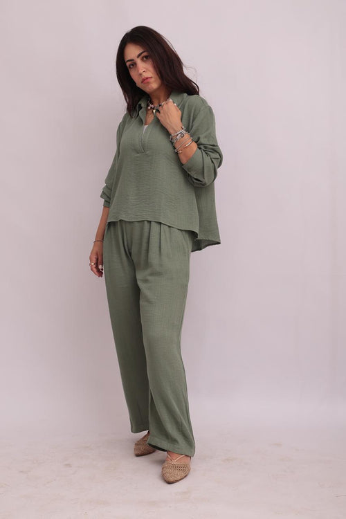 Front view of a model wearing a sage green linen pullover shirt and trousers set, looking forward.
