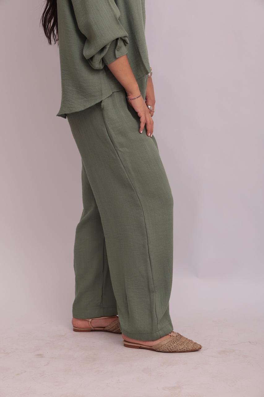 Side profile of a model wearing a sage green linen pullover collar shirt and matching wide-leg trousers, showing the relaxed drape.