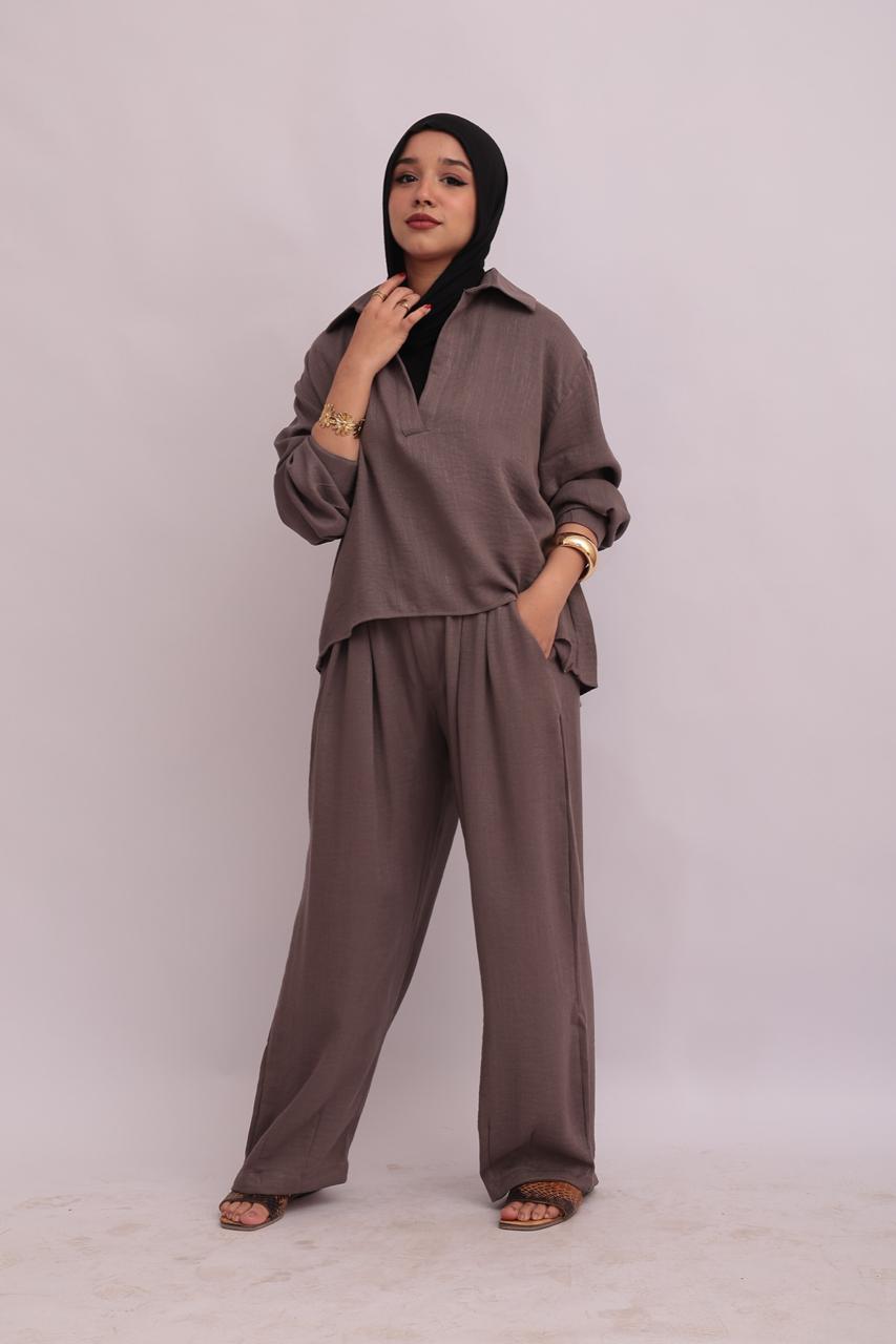 Full-body shot of a model in a black hijab wearing a taupe linen pullover collar shirt and matching wide-leg trousers.