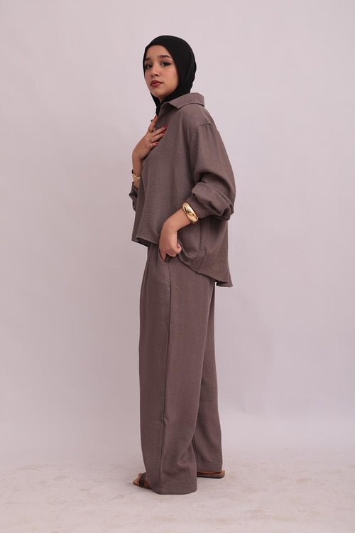 Close-up front view of a model wearing a taupe linen pullover shirt and trousers set, showing the collar structure.